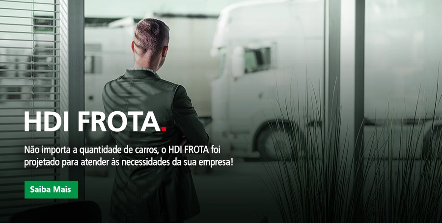 Homem de braços cruzados e vestindo um terno olhando para um caminhão branco estacionado do lado e fora